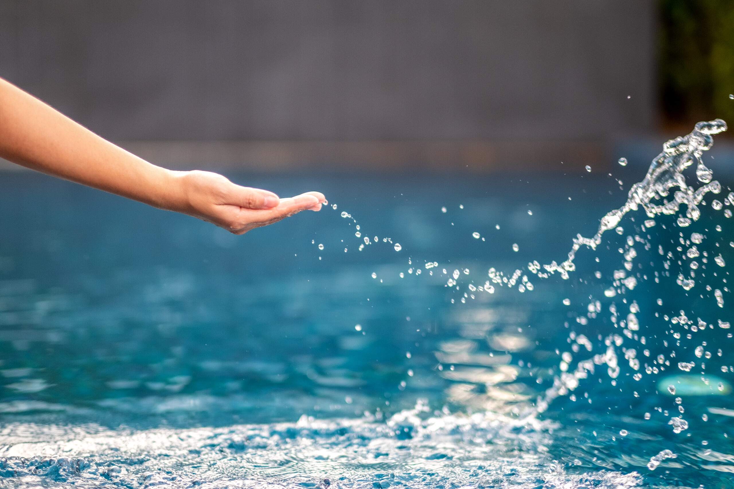 Closeup image of a hand splashing water in the pool